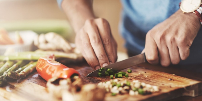 An image of hands chopping vegetables on a chopping board