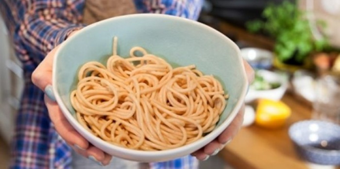 person holding a bowl with a portion of pasta