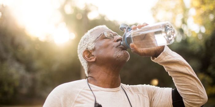 Que dois-je boire pour rester hydraté ? person walking outdoors, drinking water from a bottle