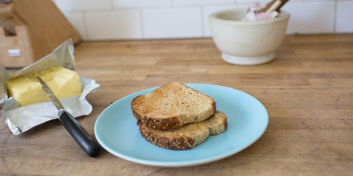 two pieces of toast on a plate with a stick of butter next to it