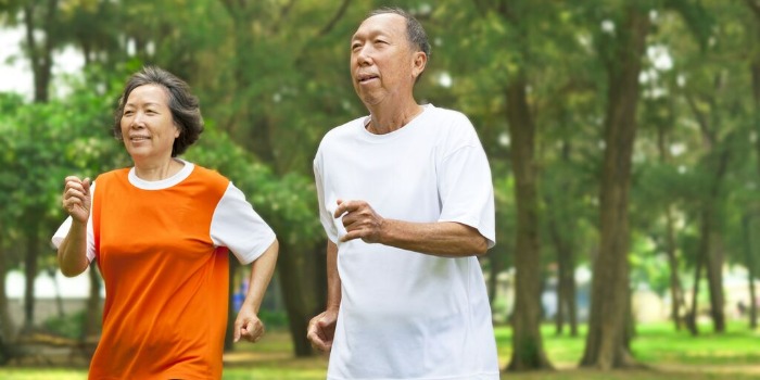 two elderly people running in the park