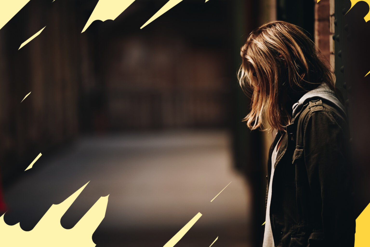 female-leaning-against-the-wall-looking-down-in-hallway-with-blurred-background suffering from childhood truama