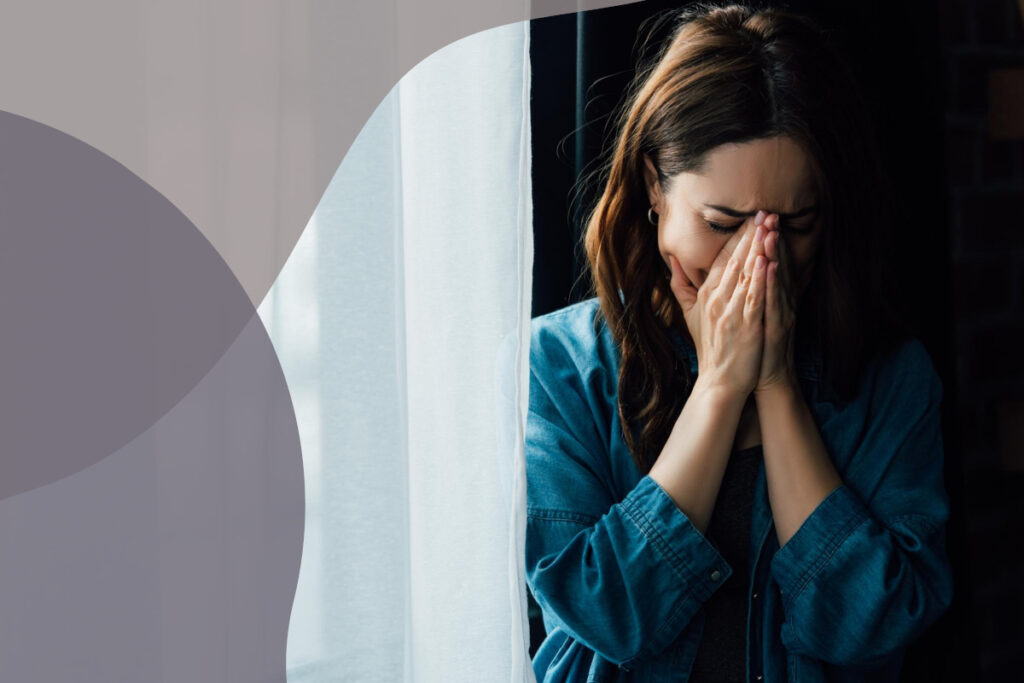 woman crying in the dark next to the window curtain