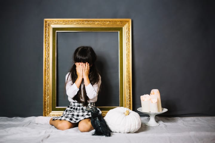 Comment endurcir un enfant sensible – Raising Tough Child Girl covers up face in front of a golden picture frame - how to toughen up your kid