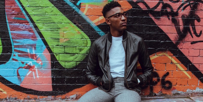 man sitting by a graffiti wall