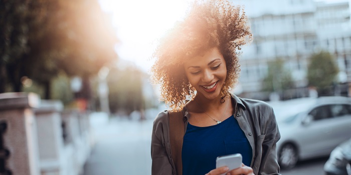 woman walking outdoors looking at her mobile phone