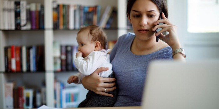 person holding a baby while on the phone and laptop