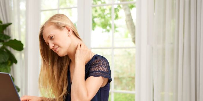 person speaking to a doctor online holding neck in pain