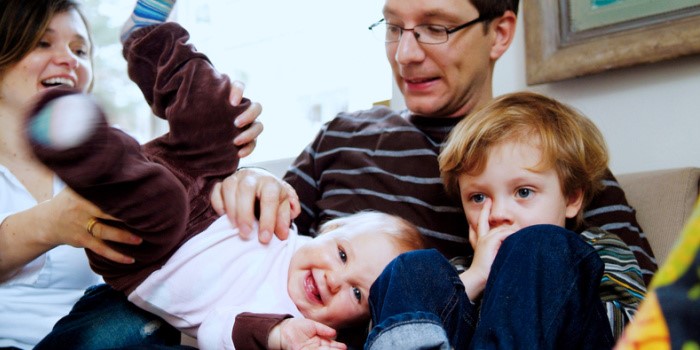 adults and toddlers laughing, playing on the sofa