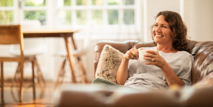 Kits de dépistage du papillomavirus à domicile – tout ce qu’il faut savoir A woman relaxing with a cup of coffee on a sofa