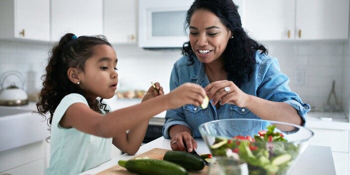adult chopping and cooking courgettes with a toddler