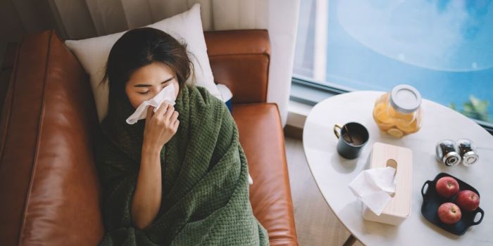Qu’est-ce que les allergies saisonnières ? A person blowing their nose, lying on the sofa