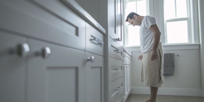 Cinq mythes sur la perte de poids person checking weight on a scale at home