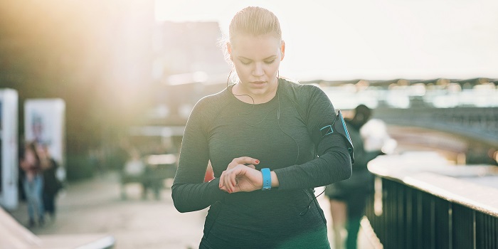 Reprendre la course à pied après la grossesse et l’accouchement woman checking her smart watch outdoors