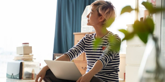 person sitting with folded legs with laptop on lap