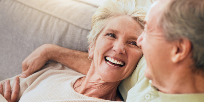 two older people sitting on a sofa, sharing a laugh