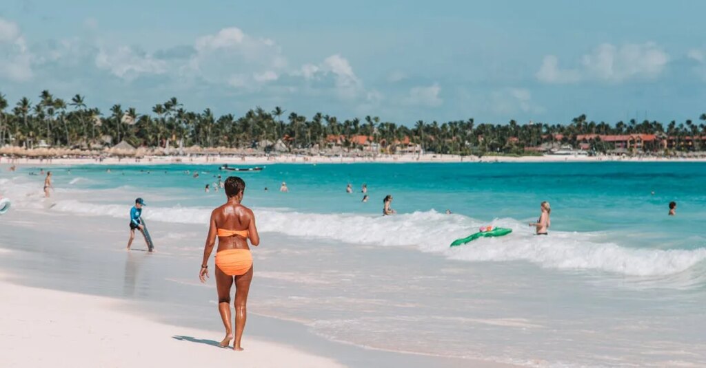 Woman walking on white sand beach with turquoise water and palm trees in Punta Cana