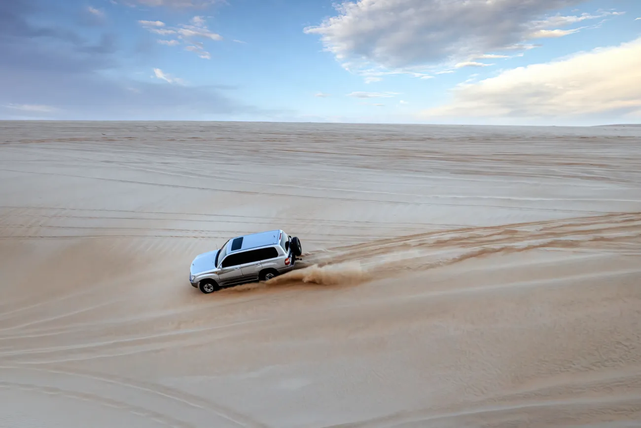 Un Toyota Land Cruiser gravissant la montagne du désert dans les dunes de sable de Sealine, Mesaieed, Qatar.