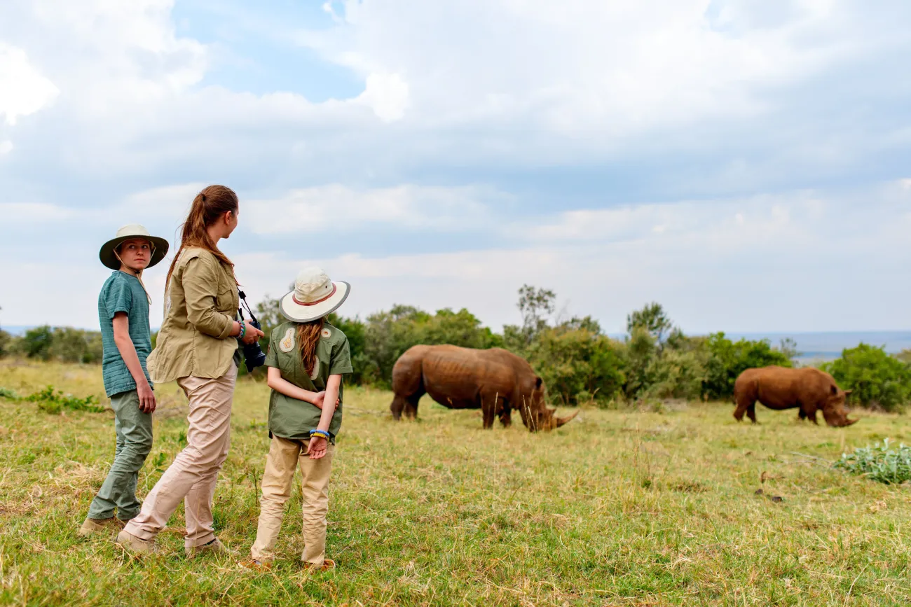 Vue arrière de la famille en safari marchant près du rhinocéros blanc
