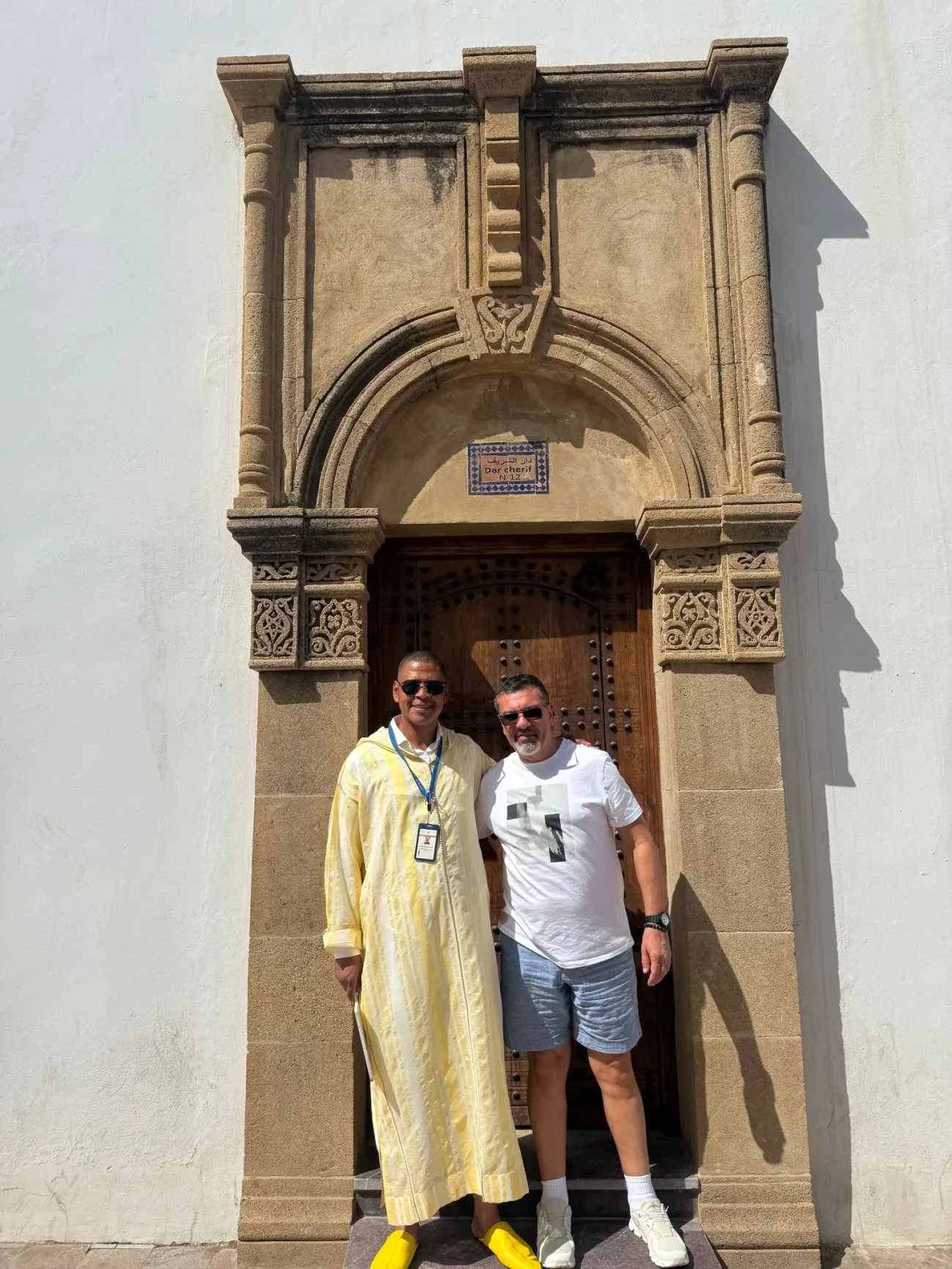 Porte voûtée sculptée et ornée avec deux hommes posant devant elle lors d'un voyage au Maroc