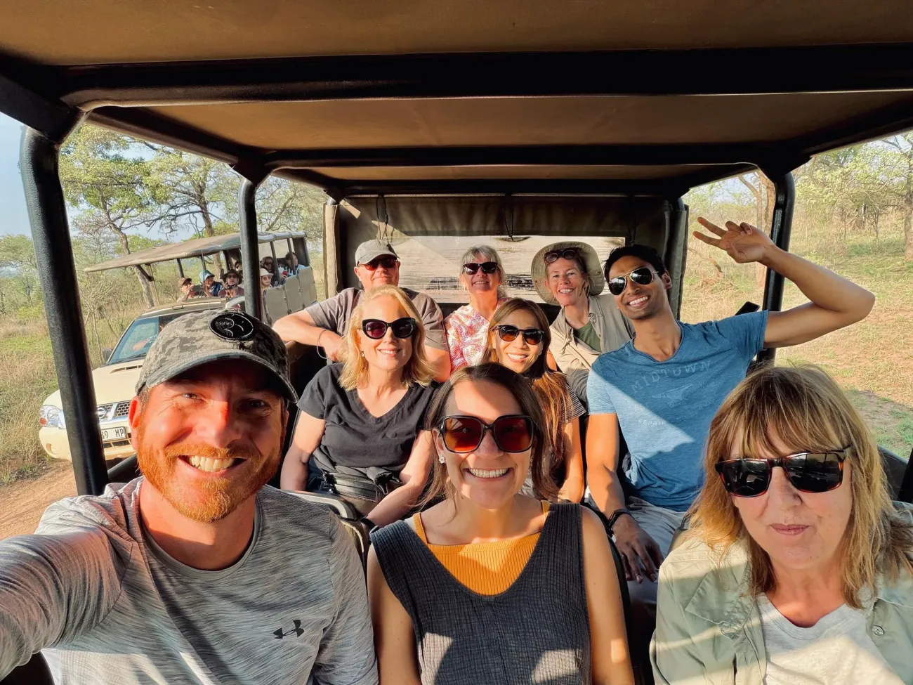 Groupe de voyageurs souriant dans un véhicule de safari ouvert lors d'un voyage dans le parc national Kruger, en Afrique du Sud.