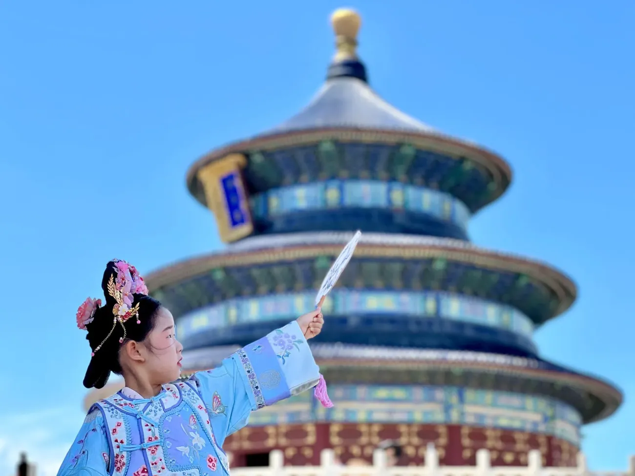 Temple du Ciel à Pékin avec une fille en costume traditionnel tenant un éventail au premier plan lors d'une séance photo