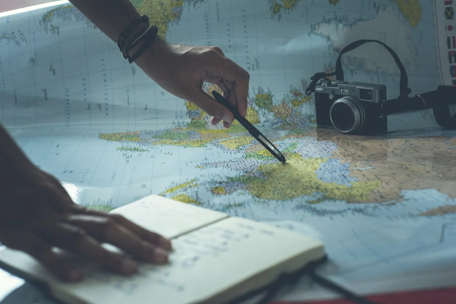 Comment nous calculons le classement des meilleurs forfaits vacances d'Exoticca person pointing a pen on a map and writing on white paper